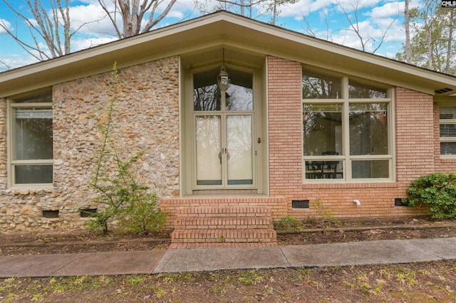 property entrance featuring crawl space and brick siding