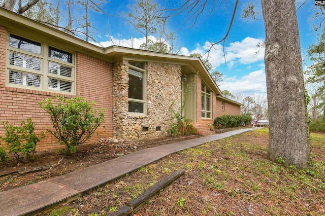 view of property exterior featuring crawl space and brick siding