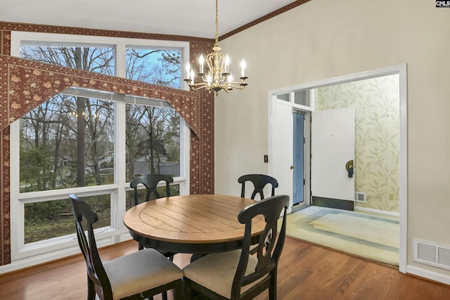 dining space featuring an inviting chandelier, wood finished floors, and visible vents