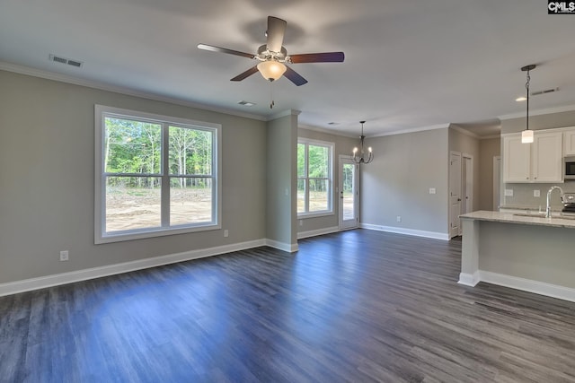 unfurnished living room with visible vents, crown molding, baseboards, ceiling fan with notable chandelier, and dark wood-style floors