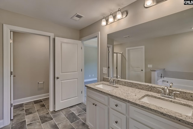 bathroom featuring a garden tub, double vanity, visible vents, and a sink