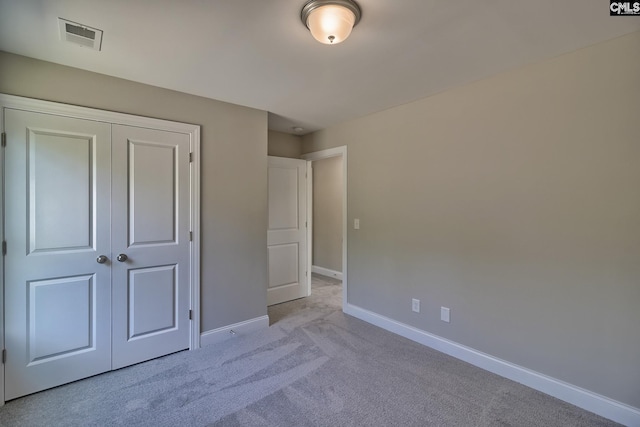 unfurnished bedroom with light colored carpet, visible vents, baseboards, and a closet