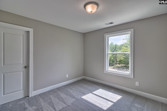 carpeted spare room featuring visible vents and baseboards