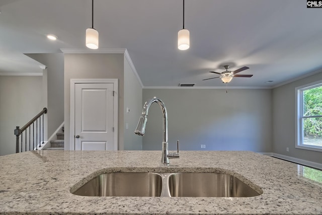 kitchen with light stone counters, ornamental molding, and a sink