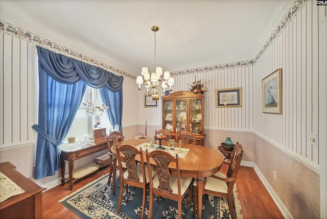 dining room with a chandelier, wallpapered walls, baseboards, and wood finished floors