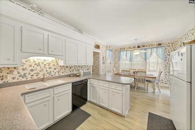 kitchen featuring wallpapered walls, black dishwasher, freestanding refrigerator, white cabinetry, and a sink