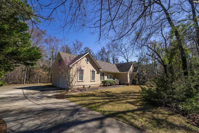 view of front facade with stucco siding, a front lawn, a garage, and driveway