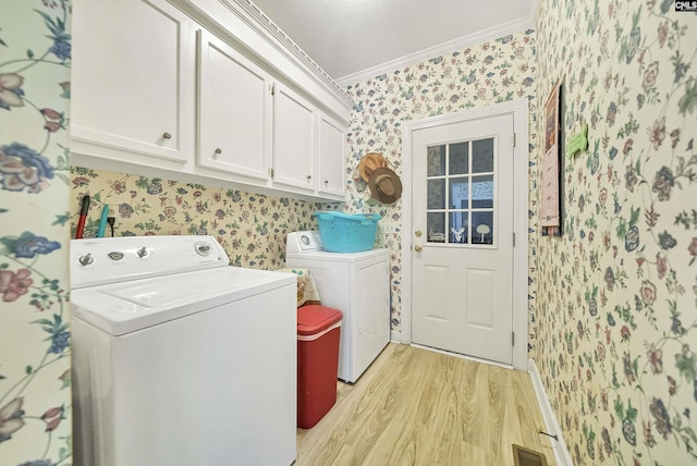 laundry area featuring wallpapered walls, ornamental molding, cabinet space, and washer and clothes dryer