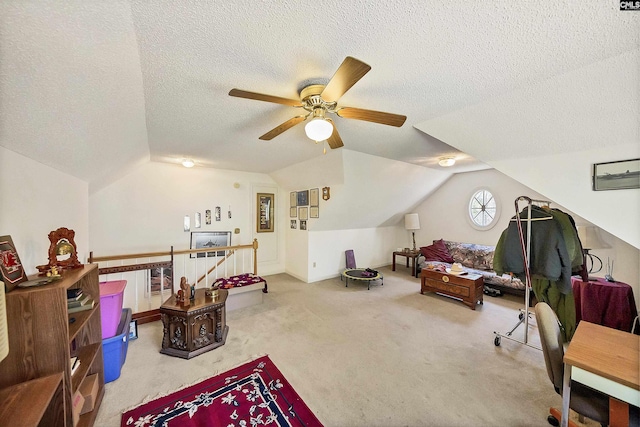 interior space with a textured ceiling, ceiling fan, carpet flooring, and vaulted ceiling