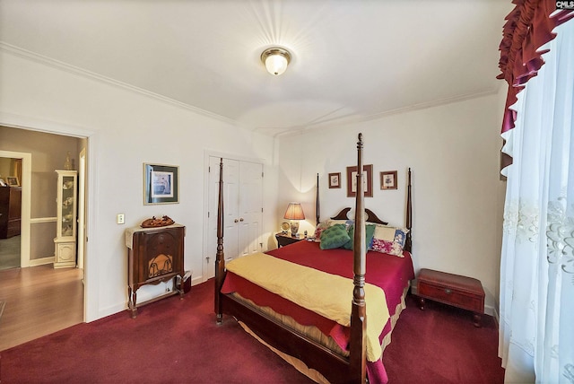 carpeted bedroom featuring crown molding, baseboards, and a closet