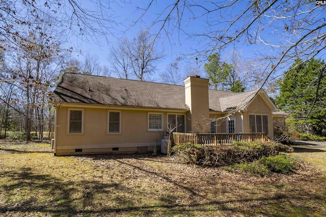 rear view of property featuring stucco siding, roof with shingles, a wooden deck, crawl space, and a chimney