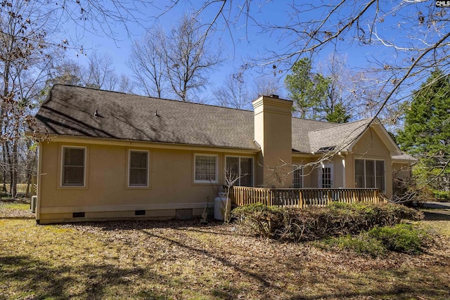 back of property with a wooden deck, a shingled roof, stucco siding, a chimney, and crawl space