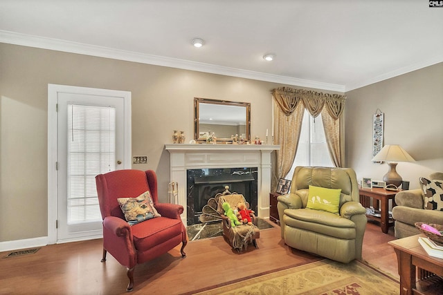 sitting room with crown molding, wood finished floors, and a premium fireplace