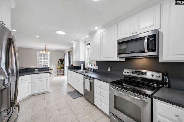 kitchen with a sink, dark countertops, stainless steel appliances, white cabinets, and light tile patterned flooring