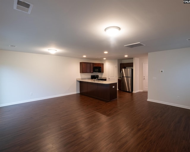 kitchen with visible vents, a peninsula, freestanding refrigerator, light countertops, and black microwave