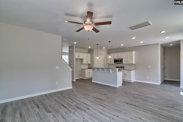 kitchen with visible vents, white cabinets, stainless steel appliances, and a kitchen bar