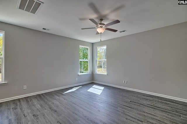 unfurnished room featuring visible vents, baseboards, and dark wood-type flooring