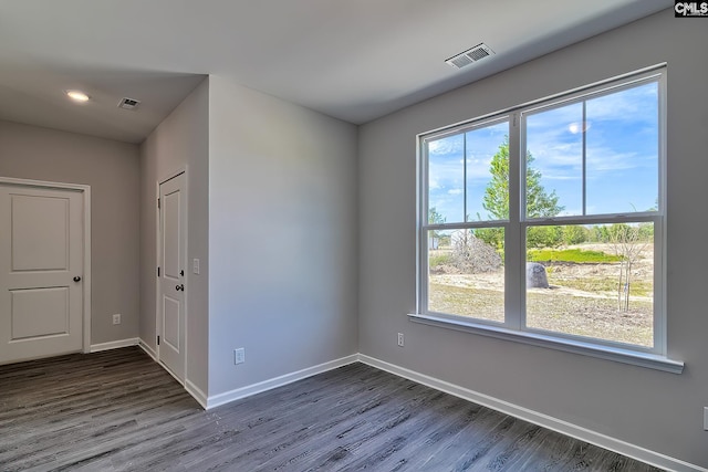 empty room with dark wood finished floors, baseboards, and visible vents