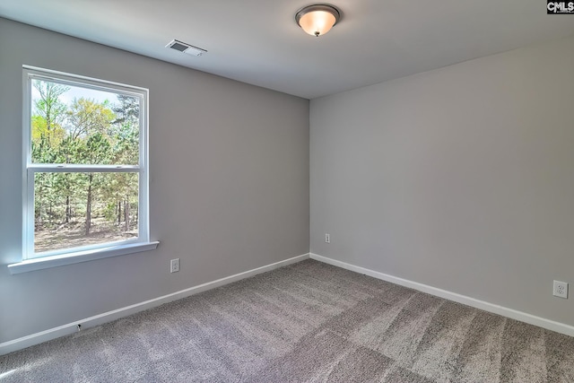 unfurnished room with visible vents, a healthy amount of sunlight, baseboards, and carpet floors