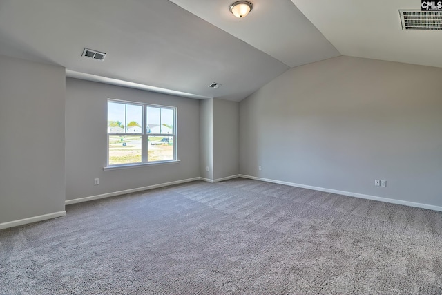 carpeted empty room with visible vents, baseboards, and vaulted ceiling