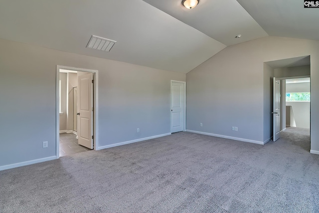 spare room with visible vents, baseboards, lofted ceiling, and carpet