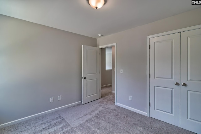 unfurnished bedroom with a closet, carpet flooring, and baseboards