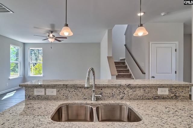 kitchen featuring a sink, visible vents, light stone counters, and wood finished floors