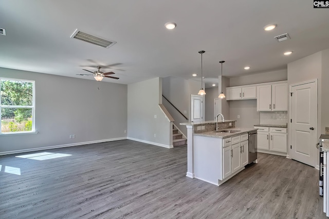 kitchen with a sink, visible vents, light wood-style floors, and decorative backsplash