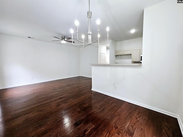 unfurnished living room featuring dark wood-style floors, visible vents, ceiling fan with notable chandelier, and baseboards