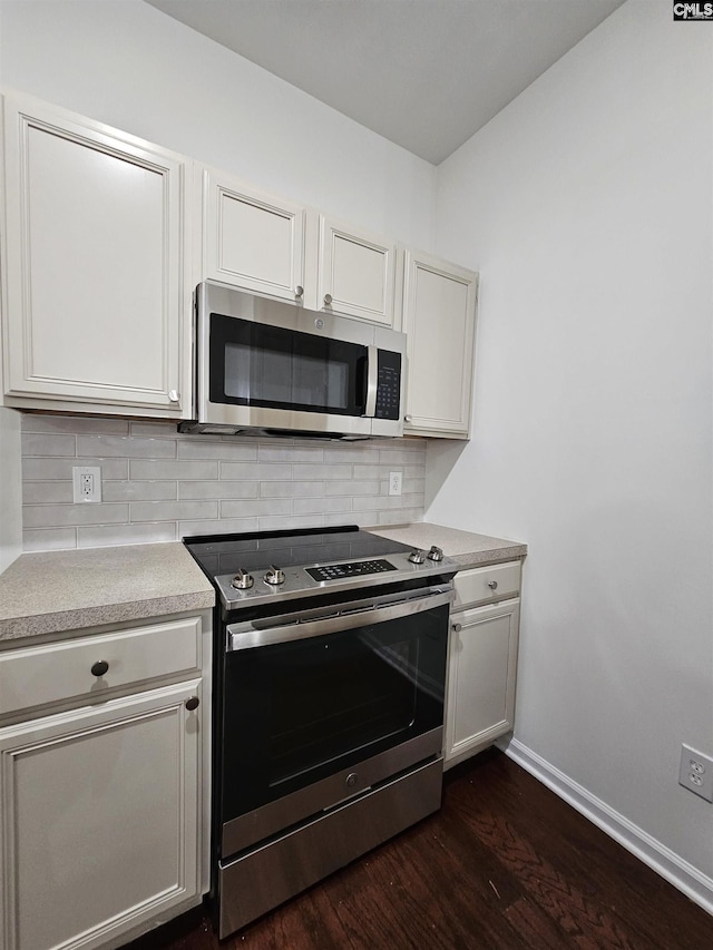 kitchen with baseboards, decorative backsplash, light countertops, dark wood-type flooring, and appliances with stainless steel finishes