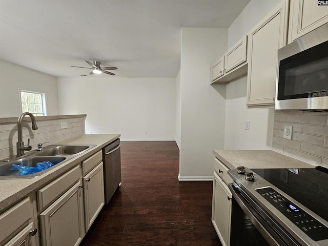 kitchen featuring a ceiling fan, baseboards, a sink, dark wood-type flooring, and appliances with stainless steel finishes