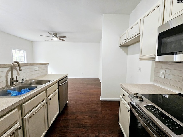 kitchen featuring baseboards, a sink, decorative backsplash, dark wood-type flooring, and stainless steel appliances