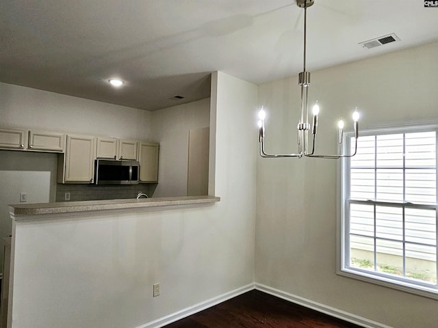 kitchen featuring dark wood finished floors, stainless steel microwave, baseboards, and visible vents