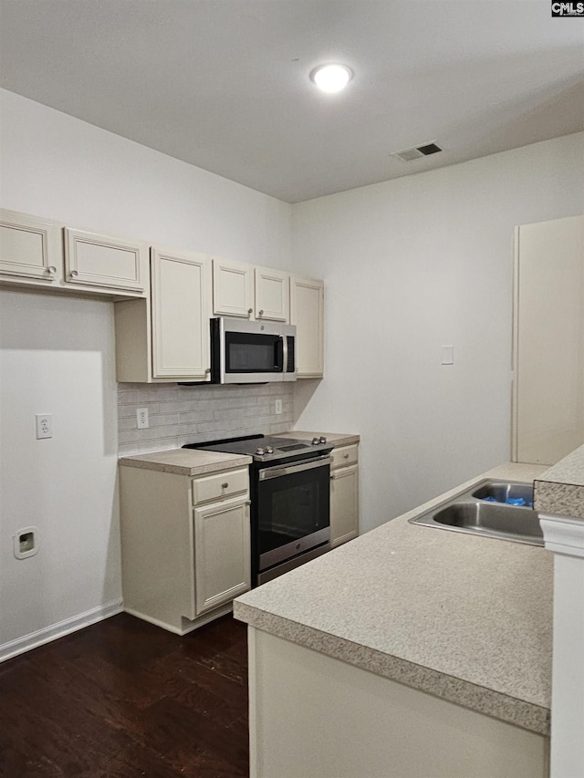 kitchen featuring visible vents, backsplash, dark wood-type flooring, stainless steel appliances, and a sink