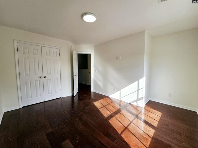 unfurnished bedroom with wood finished floors, baseboards, and a closet