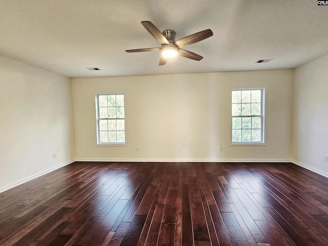 spare room featuring dark wood-style floors, visible vents, and baseboards