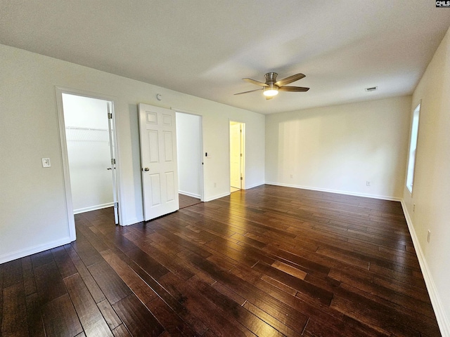 unfurnished room featuring baseboards, dark wood finished floors, and a ceiling fan