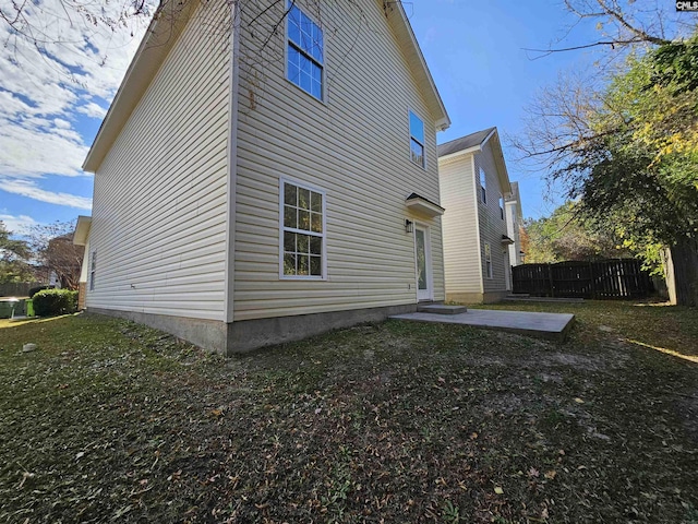 view of side of home with a yard, a patio, and fence