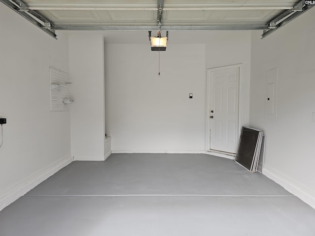 garage featuring electric panel, a garage door opener, and baseboards