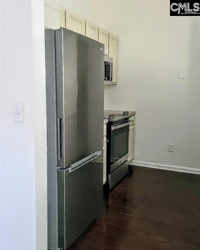 kitchen featuring baseboards, appliances with stainless steel finishes, and dark wood-style floors