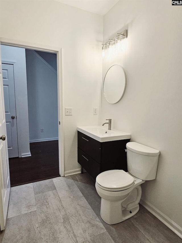 bathroom with toilet, vanity, and baseboards