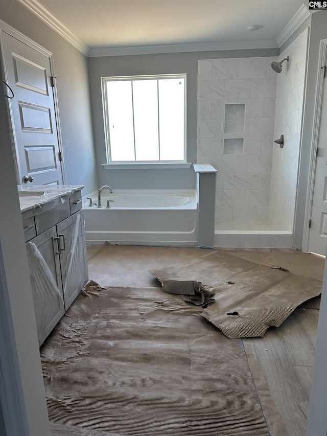 bathroom with wood finished floors, crown molding, tiled shower, a bath, and vanity