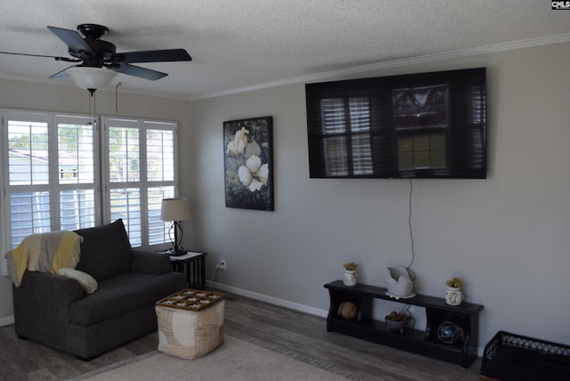 living area with crown molding, wood finished floors, baseboards, and a textured ceiling