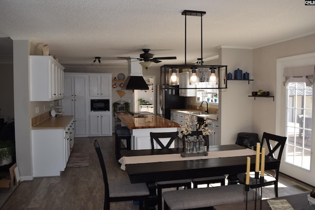 dining space with a textured ceiling, dark wood-type flooring, ceiling fan, and ornamental molding