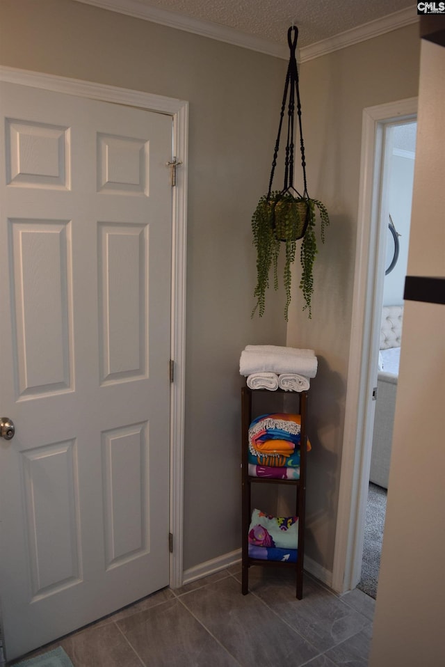 interior space with a textured ceiling, baseboards, and ornamental molding