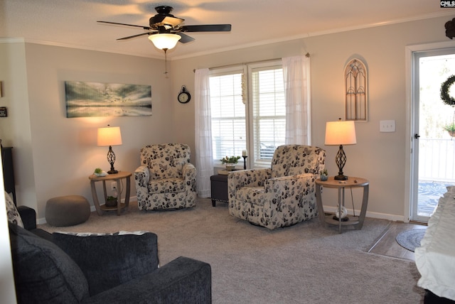 living area featuring carpet flooring, ceiling fan, baseboards, and ornamental molding