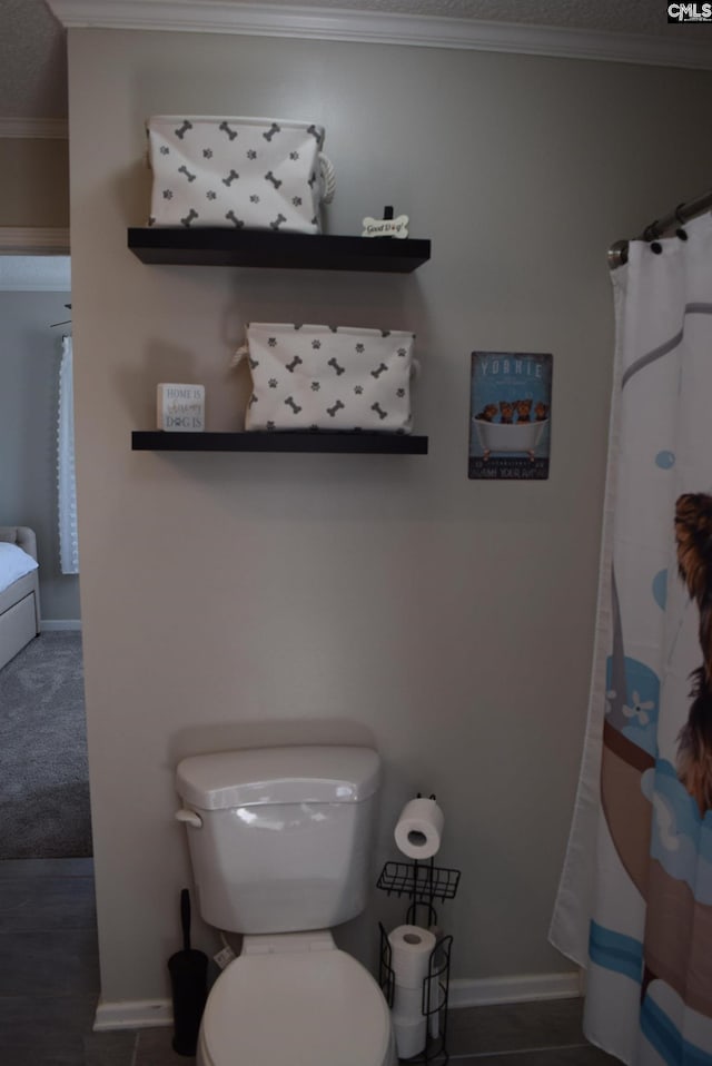 bathroom with crown molding, toilet, and baseboards