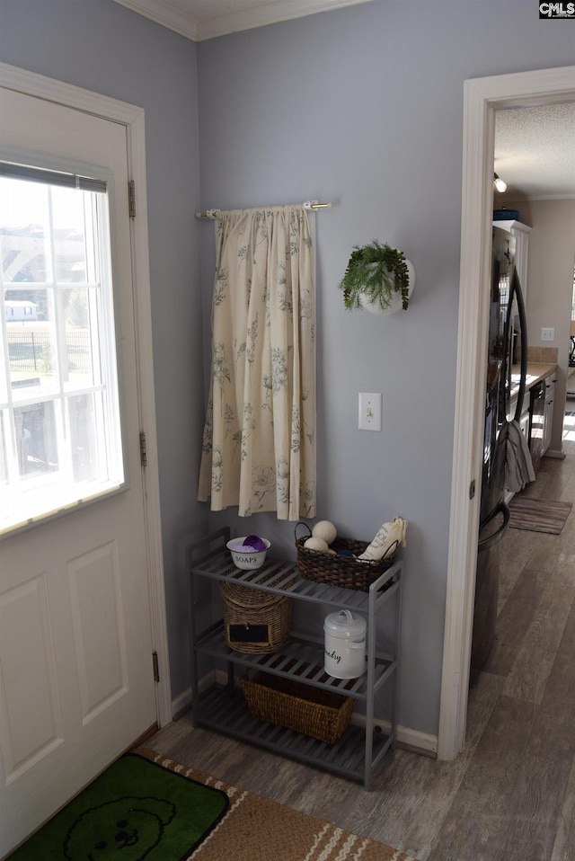 doorway featuring crown molding, baseboards, and wood finished floors