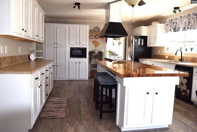 kitchen featuring white cabinetry, black appliances, island exhaust hood, and butcher block countertops