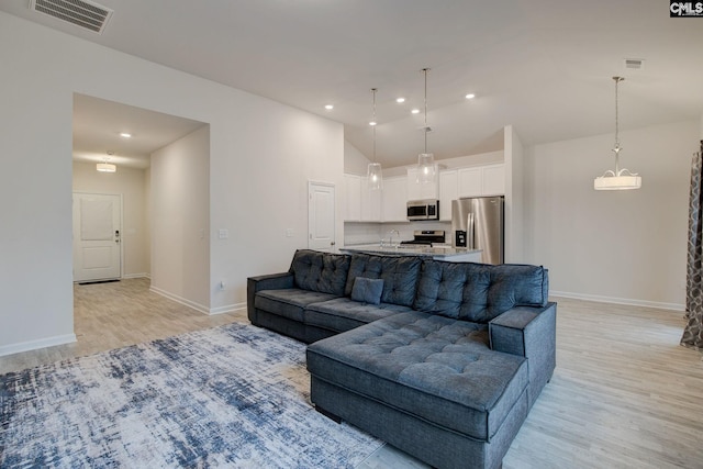 living area featuring visible vents, high vaulted ceiling, recessed lighting, light wood finished floors, and baseboards